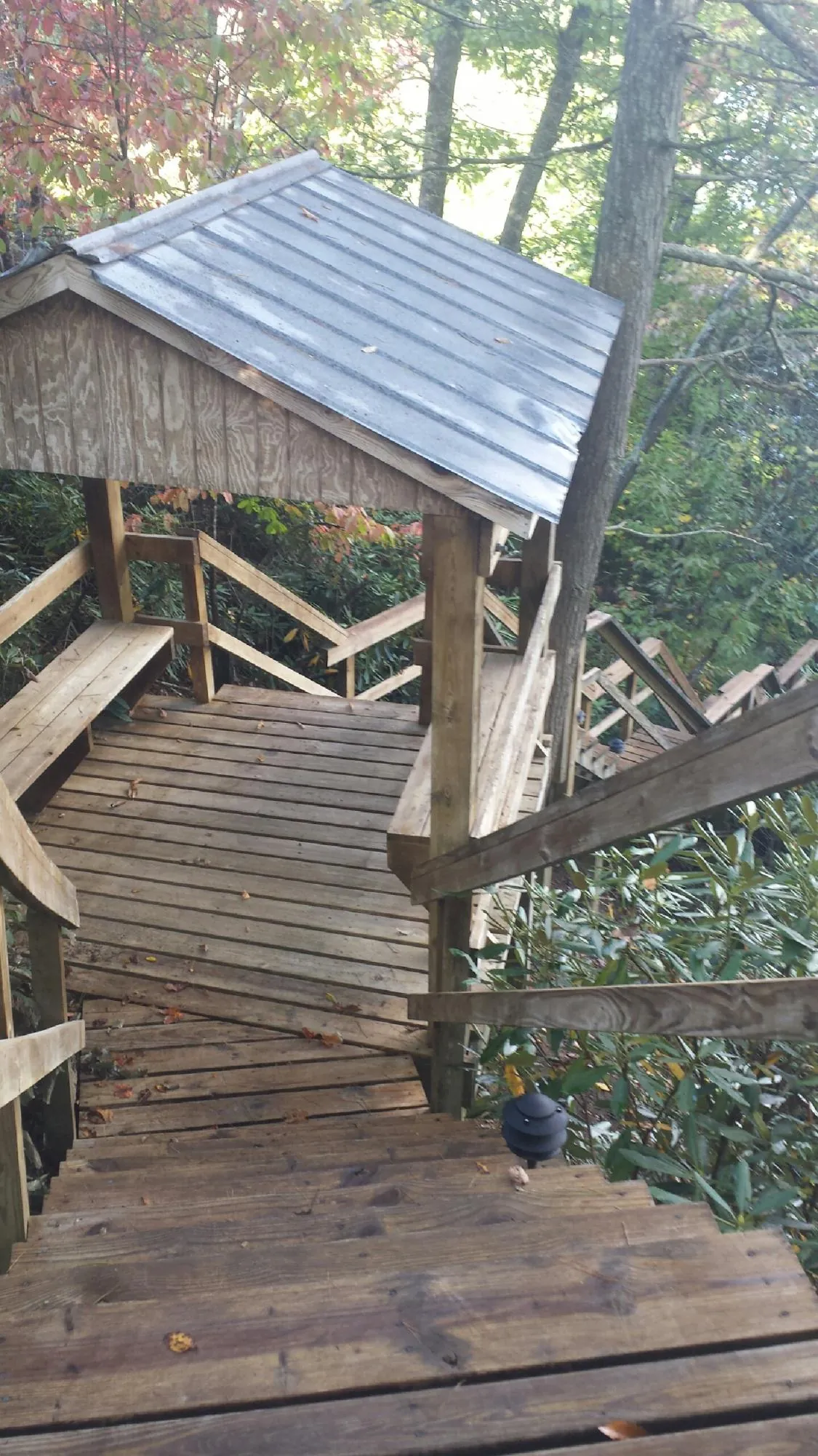 Metal roofed shelter over wooden steps on a wooded walkway — Skylight Repair & Installation work by our crew in Erie